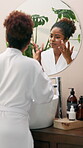 Skincare, cream and mirror with woman in bathroom for self care, glow and facial treatment. Cosmetics, grooming and vitamin c lotion with person at home for dermatology, beauty and reflection