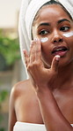 Happy, black woman and skincare with face cream or mirror in bathroom for moisturizer or cosmetology. Female person, hygiene or towel with cosmetics, lotion or creme for facial treatment at home spa