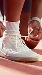 Person, hands and tying with shoes for fitness, sport game preparation or outdoor exercise on court. Closeup, athlete or tennis player getting ready with sneakers or tie laces for start or match