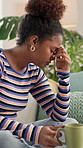 Frustrated, black woman or stress with headache or coffee on sofa for mistake or depression at home. Tired, female person or migraine with anxiety or drink for fatigue, burnout or overworked at house