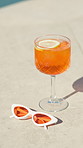 Orange, cocktail and sunglasses with glass by pool for hospitality at summer getaway or resort. Empty, drink or cool mocktail with lemon or shades for weekend vacation, party or vitamin C by poolside
