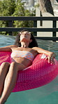 Woman, relax and swimming pool with inflatable for vacation, summer holiday or outdoor weekend at luxury resort. Calm, person or relaxation with sunglasses on float for vitamin D, break in water
