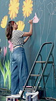 Mural, woman and creative painting for art, flower decoration and student with design outdoor. City, color and artist with brush on wall for culture, diy and floral hobby with community project