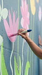 Person, hands and artist with paintbrush with wall art for floral design, colorful creativity or community service. Closeup, volunteer or stroke with paint for pink flower, mural activity or charity