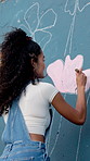 Artist, color and painter with brush on mural for community project, hobby and charity in city. Art, woman and painting on wall for flower decoration, back and volunteer with creative design outdoor