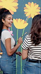 Women, happy and together with painting mural for flowers, art and design for community in urban town. Girl, painter and friends with social responsibility, creative or volunteer for building in city