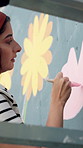 Woman, artist and painting with wall art for mural activity, community service or exterior decoration. Female person, volunteer or painter with brush stroke for floral design, flower or bulding color