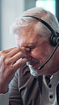 Mature man, call center and headset with headache, stress and consulting with brain fog at office. Person, migraine and customer service at help desk, pain or listen with voip connection at workplace