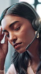 Woman, call center and headset with headache, stress and consulting with brain fog at office. Person, migraine and customer service at help desk, pain and listening with voip connection at workplace
