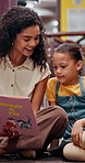 Smile, woman and child with book in library for knowledge, fantasy story and language development. Teacher, kid and help with creative novel for learning support, storytelling and reading information