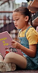 Kid, reading and book on floor in library for knowledge, fantasy story and language development. Student, studying and creative novel and academic growth, literature and information of education goal