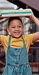 Smile, child and books on head in library for knowledge, research and information on project. Happy, student and walk with novel for creative reading, literature development and studying for learning