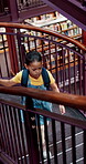Child, student and walking on stairs at library for knowledge, above or learning. Backpack, elementary or academic journey with kid for childhood development, education books or novels for school
