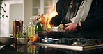 Chef, hands and stove with ingredients for cooking, hospitality or meal preparation in kitchen. Closeup, person or professional with heat or adding flavor for flame grill or culinary recipe at home