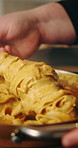 Cooking, hands and dish pasta in kitchen with plating, lunch preparation and gourmet recipe. Closeup, person and food in plate with healthy ingredients, homemade dinner and carbohydrate diet in home