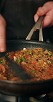 Hands, healthy food and man in kitchen, pan and cooking with recipe, wellness and ingredients. Closeup, person and chef with cuisine, home and vegetables with process, diet and culinary skills