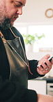 Home, internet and man in kitchen, smartphone and typing with online recipe, cooking and food blogger. Cellphone, person and chef with tech, digital app and ingredients with nutrition website