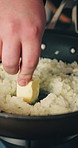 Person, hands and butter with pan of rice for starch flavor, meal or cooking on stove at home. Closeup, chef or frying with ingredients or dish for food texture, preparation or risotto in kitchen