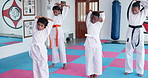 Children, students and karate with stretching in class, start or ready for exercise with taekwondo learning. Warm up, group of kids and teacher, fitness and martial arts club for self defense