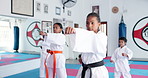 Group, karate and children exercise in dojo for fight, fitness and learning self defense in class for sports. Students, kids and practice martial arts for development, workout and punch for training