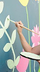 Hands, painting and art with mural on wall for flowers, art and design for community in urban town. Person, painter and leaves with social responsibility, creative and volunteer for building in city
