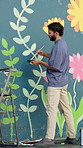 Man, painter and color for mural on wall with leaves, art and community project in urban town. Person, back and stroke brush for social responsibility, creativity and volunteer for building in Mexico