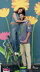 Couple, face and painting flower mural by wall, creative bonding and love with talking for DIY art project. Man, woman and hug on ladder with painter team, support and aesthetic floral design