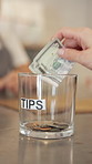 Hand, tips and person with money in glass for customer gratitude, service performance or appreciation. Closeup, client and dollar in jar for small business contribution, staff reward and cash payment