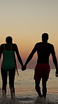 Couple, back and holding hands at beach, sunset and vacation with bonding, love and outdoor by sea in summer. People, man and woman with care, connection and waves on holiday by ocean in Brazil