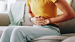 Hands, stomach pain and woman on sofa in living room of home for cramp, menstruation or pms. Abdominal, Indigestion and tummy ache with person in apartment for constipation, endometriosis or fibroids