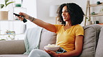 Popcorn, remote and woman watching television on sofa for entertainment in living room. Relax, snack and female person with streaming subscription for movies, film or series in lounge at apartment.