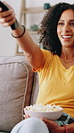 Home, remote control and woman on couch, popcorn and relax with weekend break in lounge. Entertainment, watching tv and happy person with snack, eating treat and streaming for funny movie and series