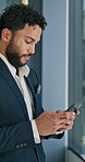 Man, phone and texting by window at office with networking, negotiation or contact at real estate agency. Person, realtor and smartphone with scroll on mobile app, notification or search for property