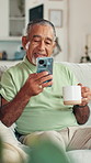 Senior man, phone and coffee on sofa with texting, scroll and contact with web chat in living room. Elderly person, smartphone and mug on with tea, latte and mobile app for social media in retirement
