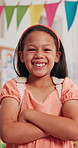Face, smile and child in class for education, learning or future development. Portrait, happy girl and confident kid in school with arms crossed for growth, scholarship or elementary student in Spain