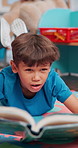 Hobby, kid or boy reading book in library for help, development or learning growth in school. Language, student or creative male child with literature lesson, fairy tale or fantasy for story time