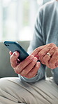 Elderly hands, phone and typing on sofa for chat notification, playing online game or browsing news blog. Retirement, senior person and closeup with smartphone for text message or download mobile app