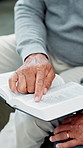 Hands, bible and religion in home, couple and together for studying, point and faith in lounge. Senior people, spiritual jewelry and book for Christian knowledge, scripture and holy gospel at house