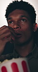 Eating popcorn, movie and man in cinema audience for premiere and entertainment. Theatre, people and suspense or closeup for show, performance and watching film with snack, spectator and release