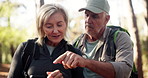Phone, hiking and senior couple in forest for direction, destination discussion or lost. Mobile, man and woman trekking outdoor, reading map and pointing for navigation app to travel to location