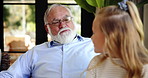 Happy, relax and grandfather with kid in home with bonding, love and family time. Smile, conversation and senior man with girl child for talking with knowledge together in living room in house.