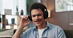 Headphones, dancing and man with smartphone on sofa in home for chatting, relaxing and listen to music. Audio tech, phone and person with networking and streaming album on mobile app in living room.