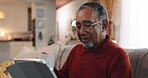 Tablet, typing and smile with old man on sofa for streaming, communication app and retirement. Subscription, contact and chat with senior person in living room at home for reading, search and online