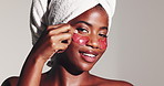 Happy, black woman and beauty with eye patches in studio for collagen on a white background. Portrait, female person or model with smile or gel mask for hydration, facial spa treatment or skincare