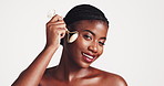 Derma roller, black woman and gua sha on face for beauty, acne or blood circulation in studio on white background. Cosmetic, quarts stone and product for lymphatic drainage, wellness and skincare