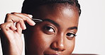 Black woman, face or eyebrows with tweezer in studio for grooming epilation on a white background. Portrait, female person or happy model with cosmetic tool for fine hair removal or beauty perfection