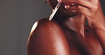 Studio, black woman and skincare with serum for shoulder, dermatology and clean shine for wellness. Female person, glow and dropper with oil for liquid cosmetics, hyaluronic acid by gray background