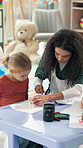 Teacher, kid and helping with drawing for activity, creativity or learning together in classroom. Woman, educator or assist with toy for tracing, fine motor skills or education at kindergarten school