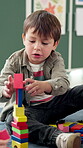 Classroom, child and boy with blocks for education, creative and cognitive development in school. Kindergarten, student and kid with building toys for learning, motor growth and problem solving skill