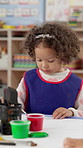 Classroom, painting and girl with creativity, kid and artistic with education, motor growth and kindergarten. Child development, student and craft in school, lesson and project with fun activity